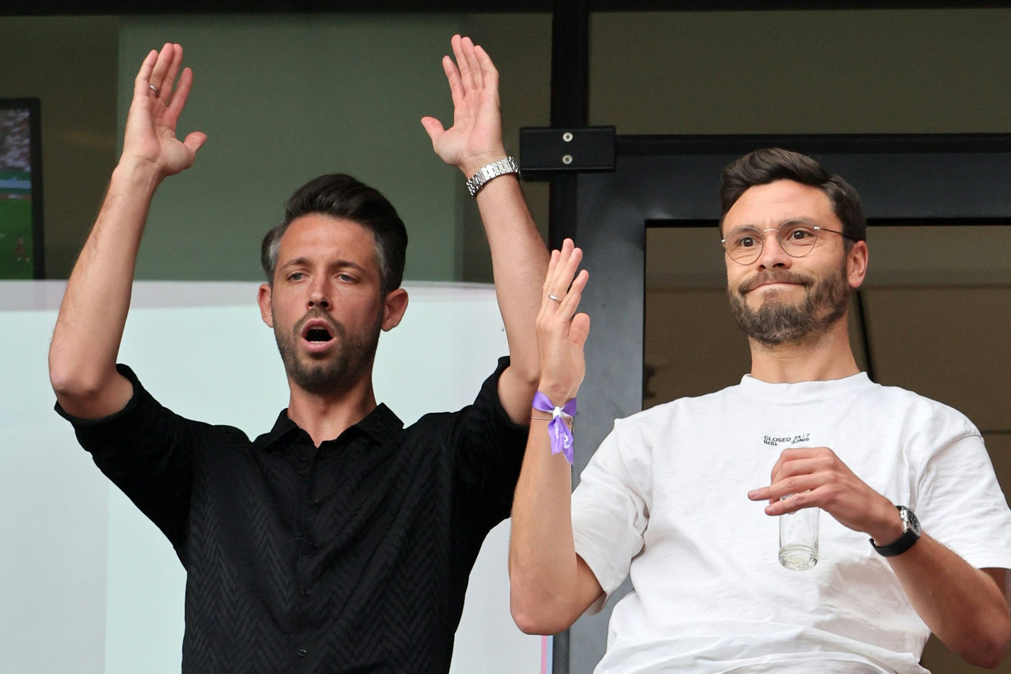 Mark Uth und Jonas Hector reagieren auf der Tribüne bei einem FC-Spieler.