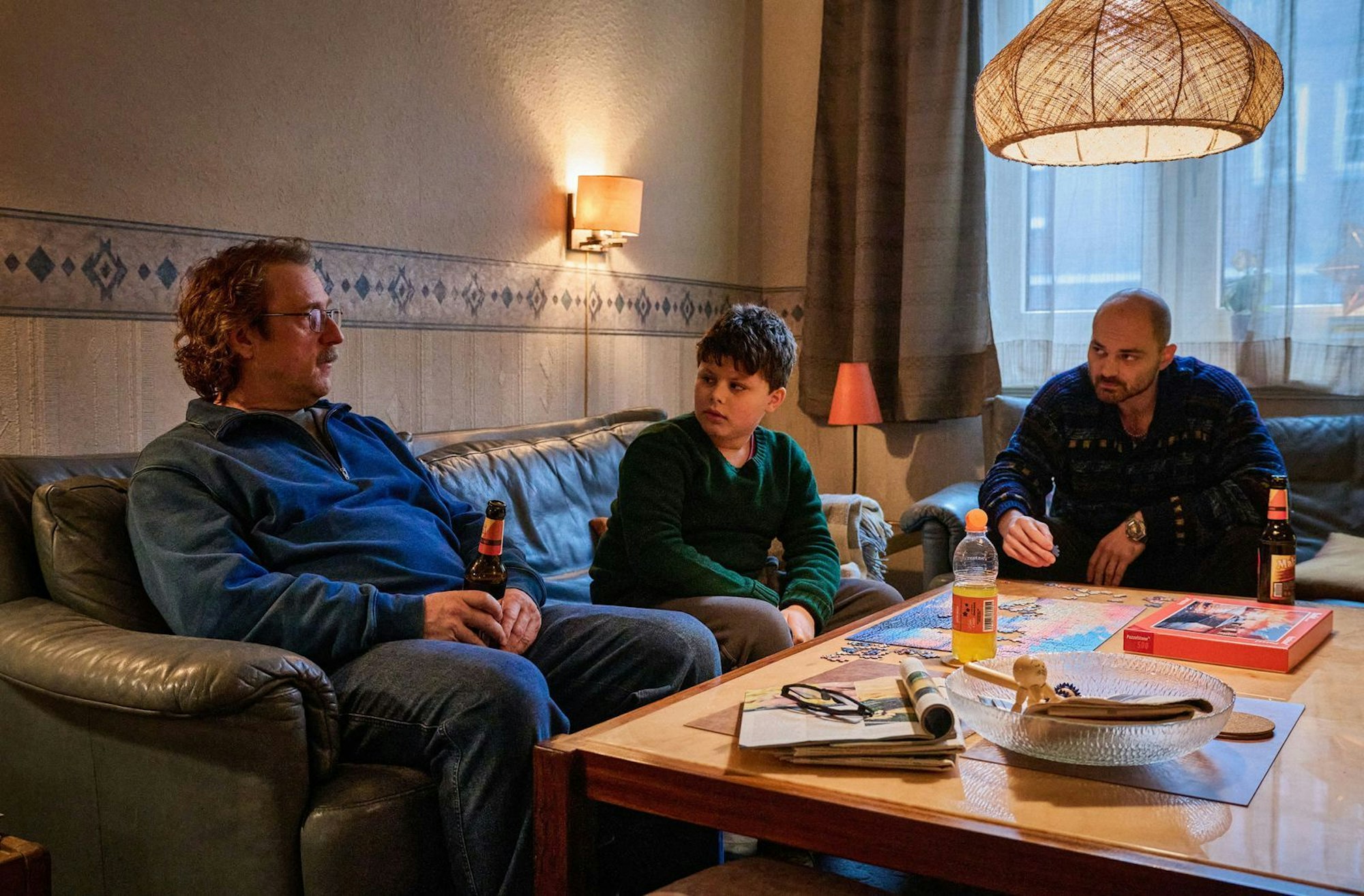 Ungleiches Trio, das gern zusammen bei Prange abhängt: Nachbarsohn Malik „Butschi“ (Samy Ghariani, zweiter von links) und Lieferdienstfahrer Micki (Božidar Kocewski, rechts) entwerfen eine Kennenlernstrategie für den schüchternen Prange (Bjarne Mädel). (Bild: NDR/Thomas Leidig)