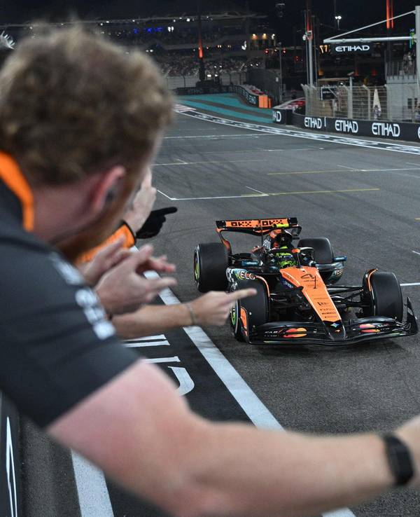 Lando Norris fährt über die Ziellinie, sein Team jubelt ihm zu.