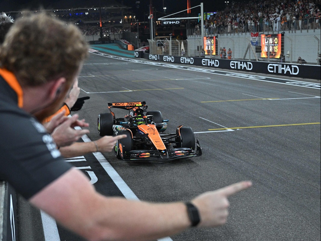 Lando Norris fährt über die Ziellinie, sein Team jubelt ihm zu.