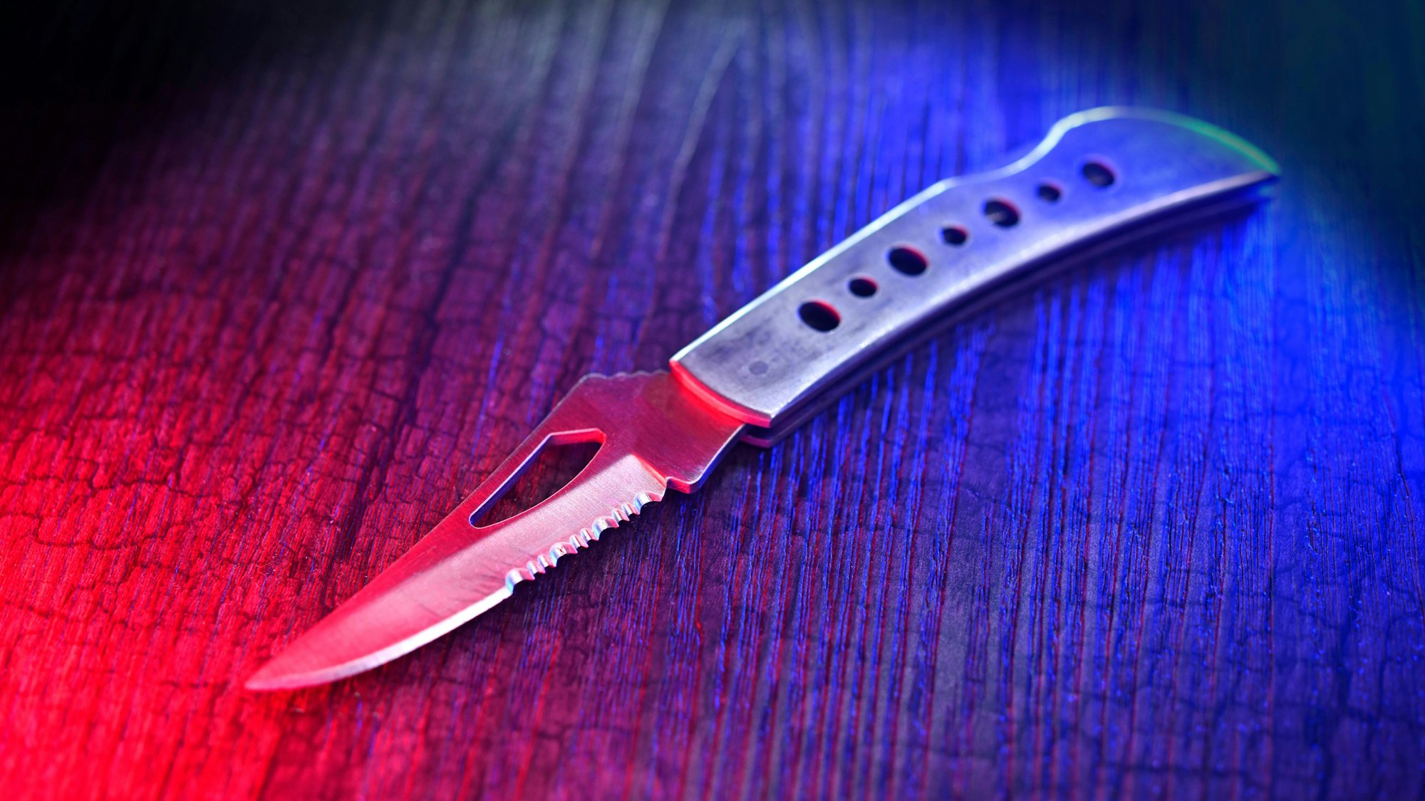 Ein Messer auf einer Holzoberfläche, beleuchtet mit rotem und blauem Licht