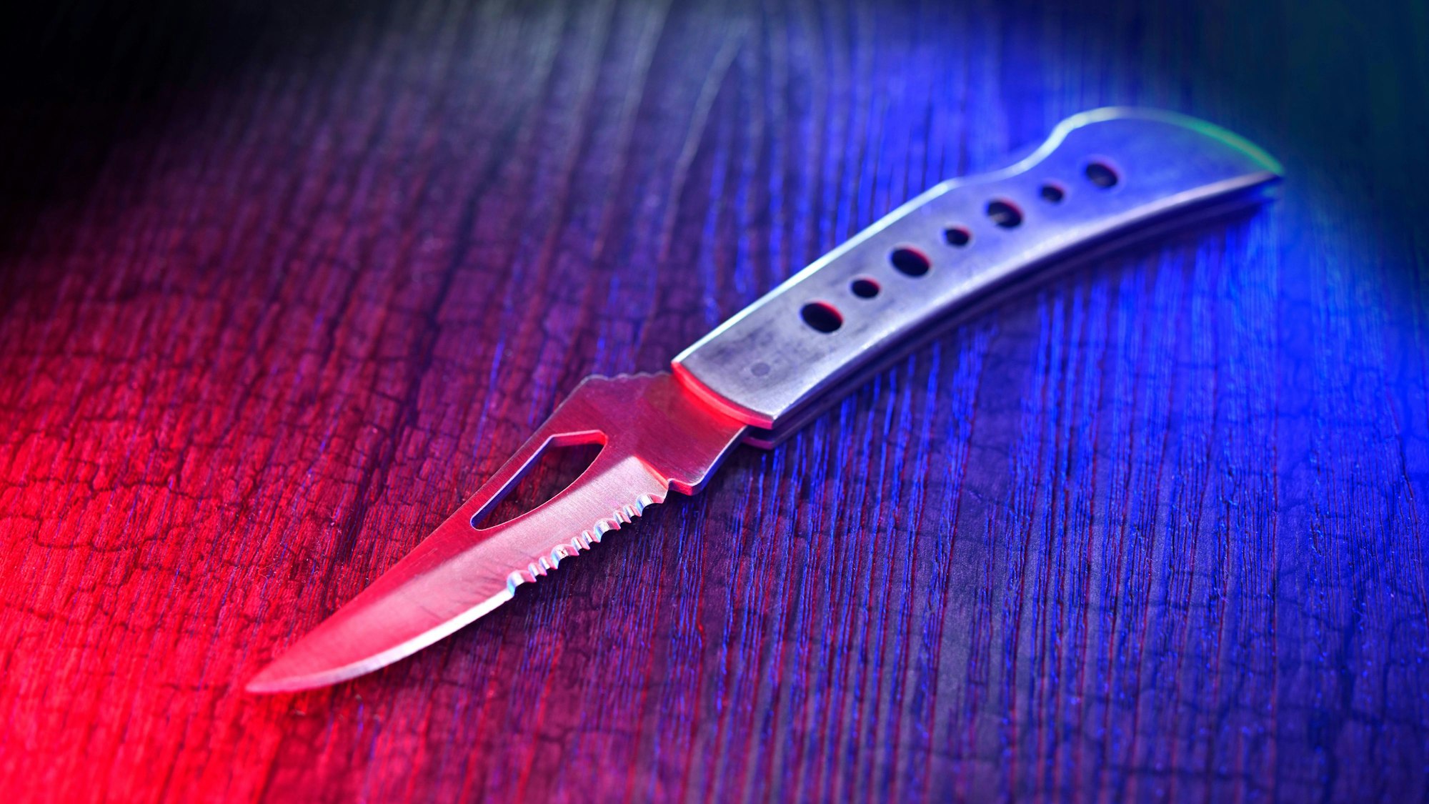 Ein Messer auf einer Holzoberfläche, beleuchtet mit rotem und blauem Licht