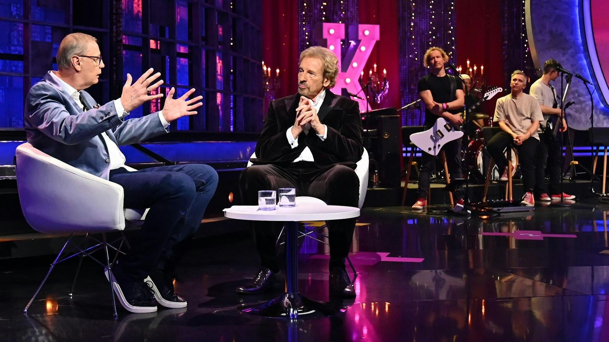 Günther Jauch spricht mit Thomas Gottschalk im TV-Studio. Im Hintergrund ist die Band Kasalla.