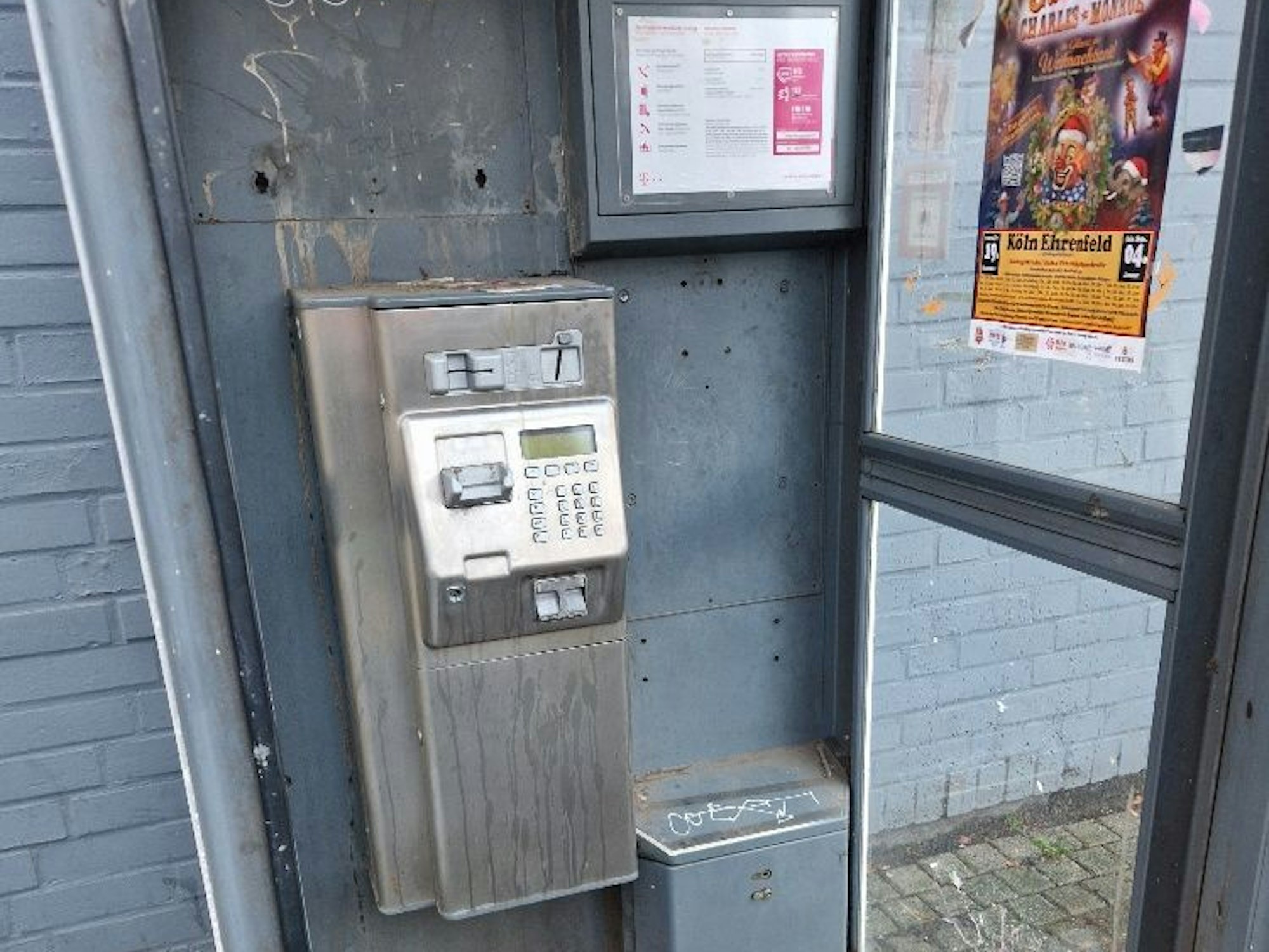 In einer Telefonzelle gibt es keinen Hörer mehr, das Telefongehäuse und die Wände sind verdreckt.