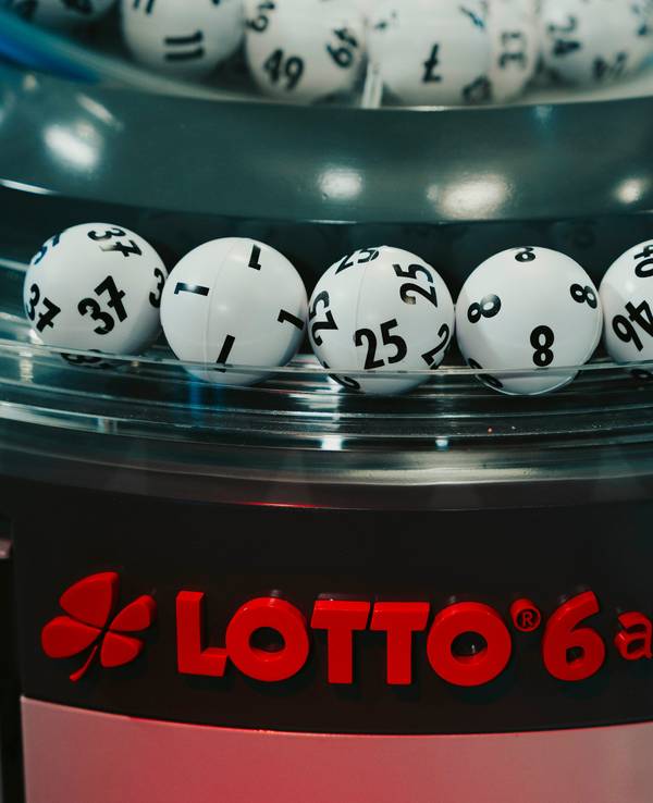 Das Bild zeigt die gezogenen Lottozahlen-Kugeln in einer modernen Ziehungsmaschine. Im Vordergrund ist das rote Logo „LOTTO 6 aus 49“ zu sehen.