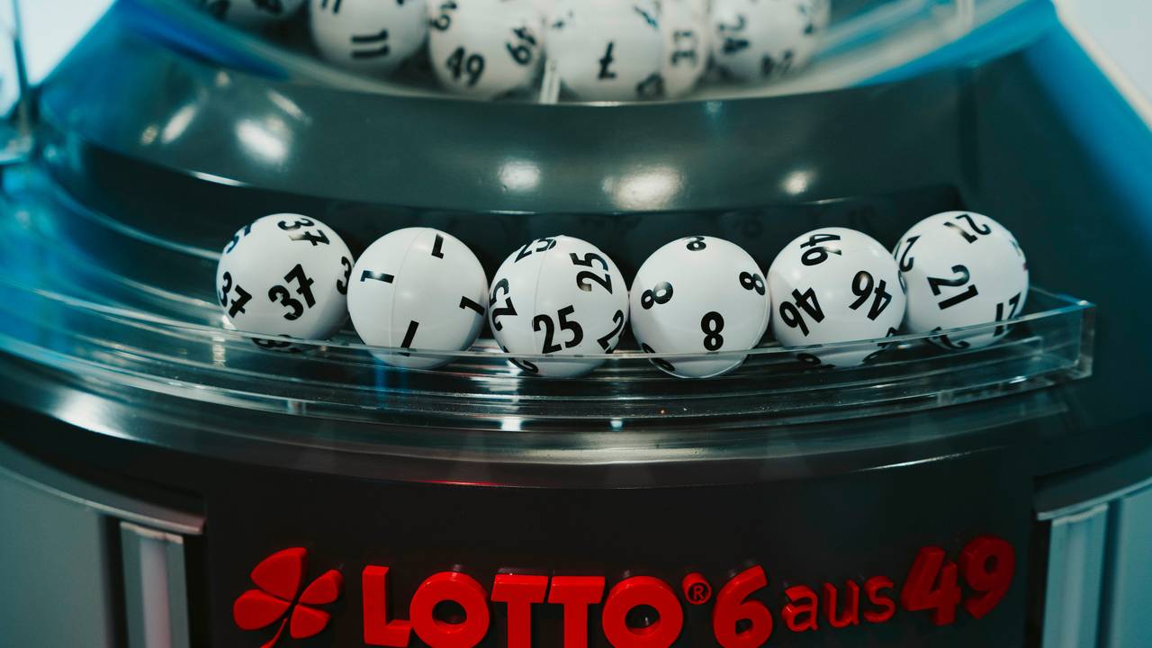 Das Bild zeigt die gezogenen Lottozahlen-Kugeln in einer modernen Ziehungsmaschine. Im Vordergrund ist das rote Logo „LOTTO 6 aus 49“ zu sehen.