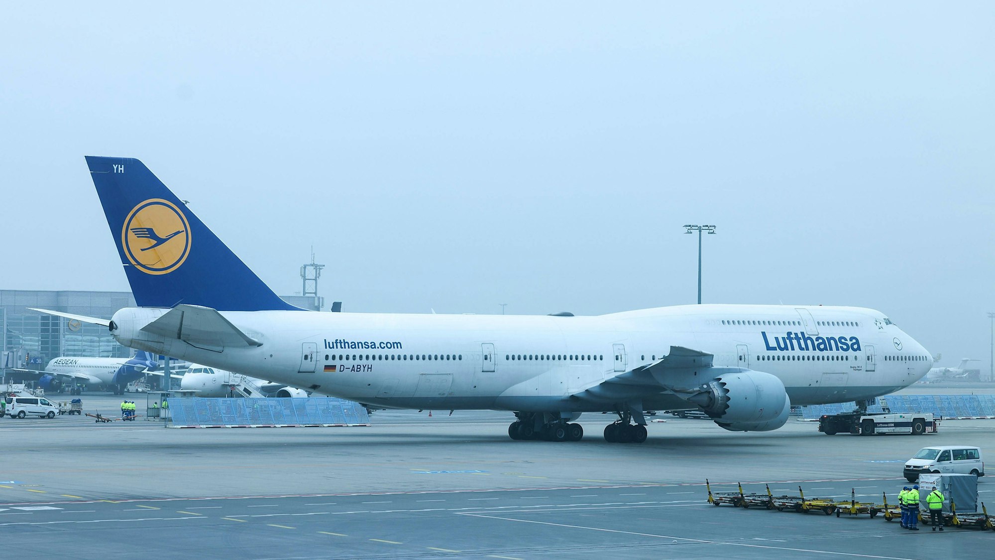 Symbolbild: Ein großes Passagierflugzeug wird auf einem nebligen Rollfeld abgeschleppt