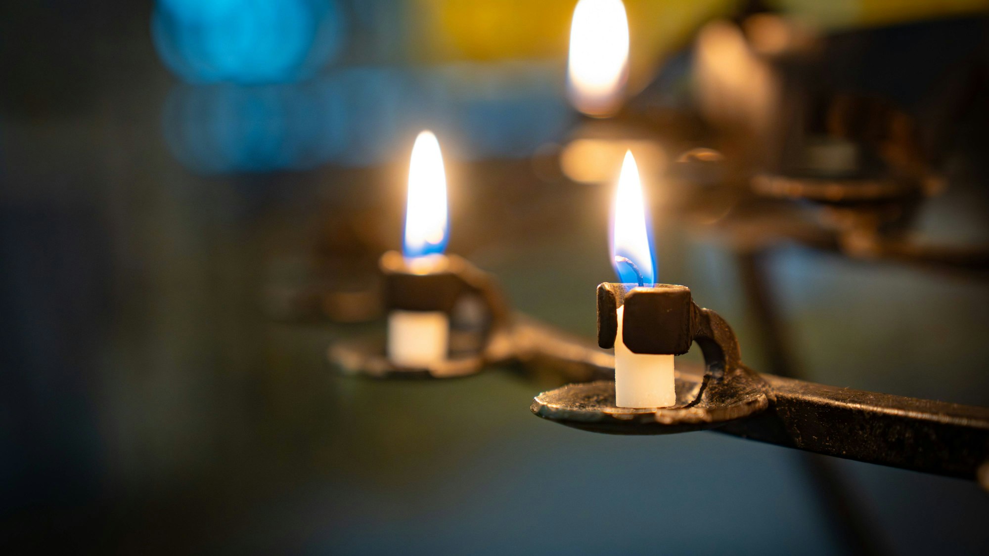 Nahaufnahme von brennenden Opferkerzen in einer Kirche mit farbig unscharfem Hintergrund