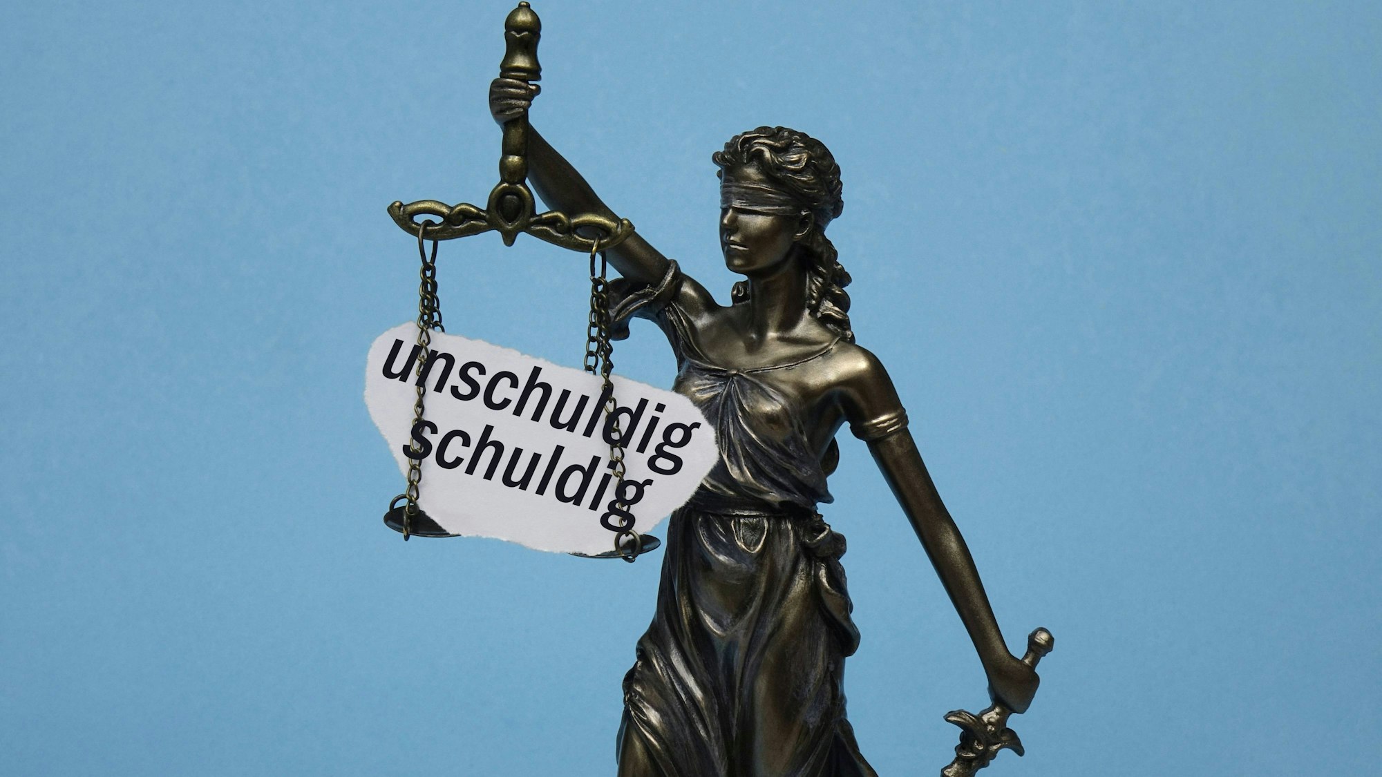 Justitia mit Waage und den Worten unschuldig und schuldig
