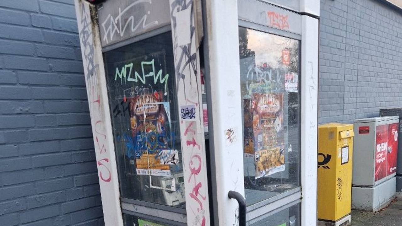 Eine Telefonzelle ist komplett beschmiert und mit Werbezetteln beklebt.