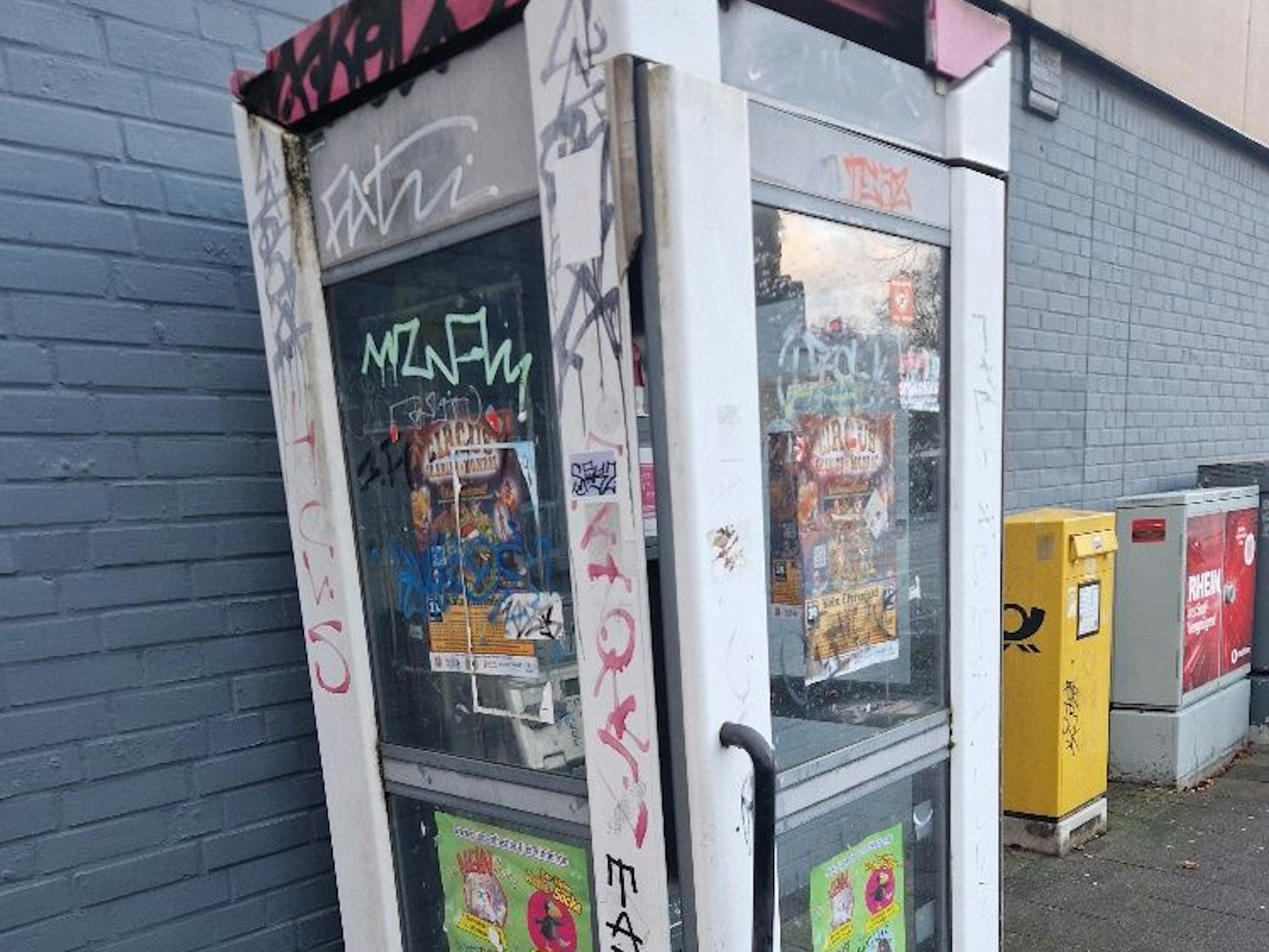 Eine Telefonzelle ist komplett beschmiert und mit Werbezetteln beklebt.