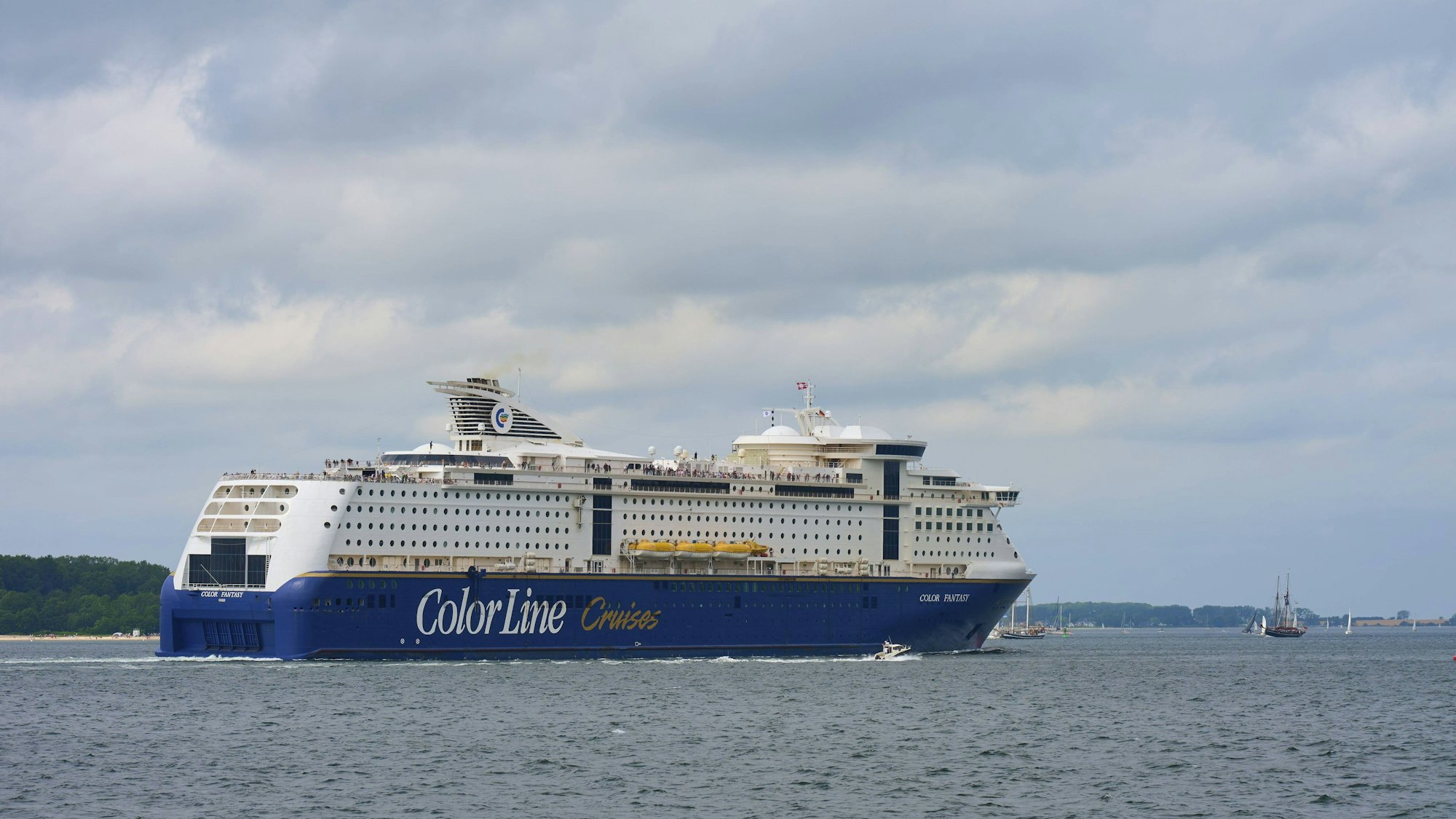 Großes Kreuzfahrtschiff mit Segelbooten auf dem Wasser unter Wolken (Symbolbild)