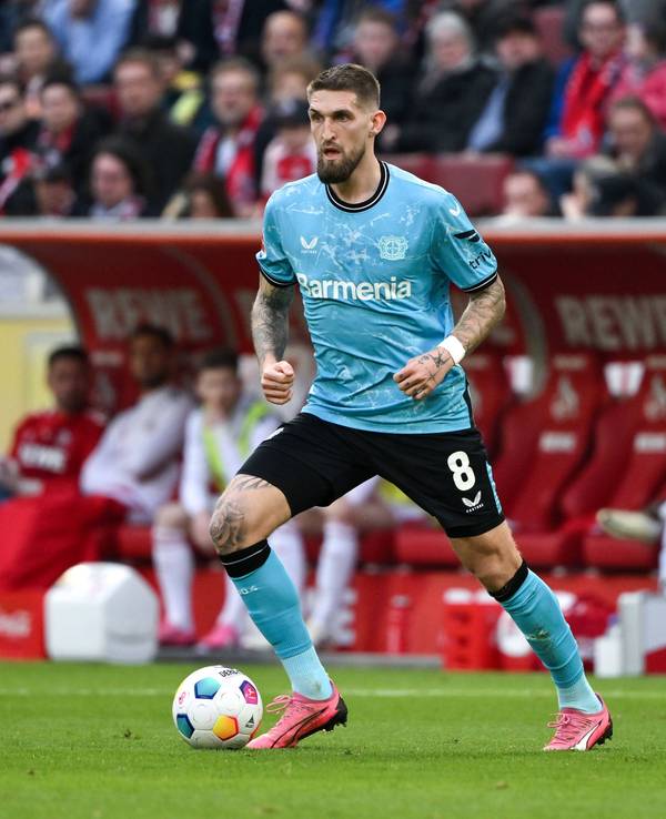 Robert Andrich dribbelt mit dem Ball, im Hintergrund sieht man die Auswechselbank des 1. FC Köln.