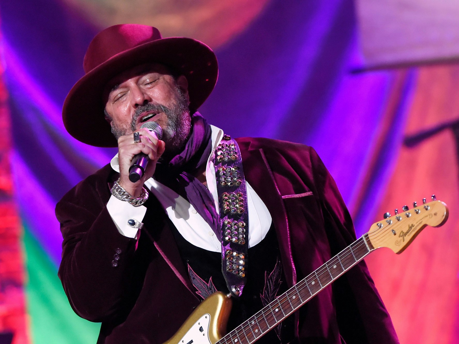 Raul Malo bei einem Auftritt, er hat eine Gitarre umgehängt und singt mit geschlossenen Augen in ein Mikrofon.