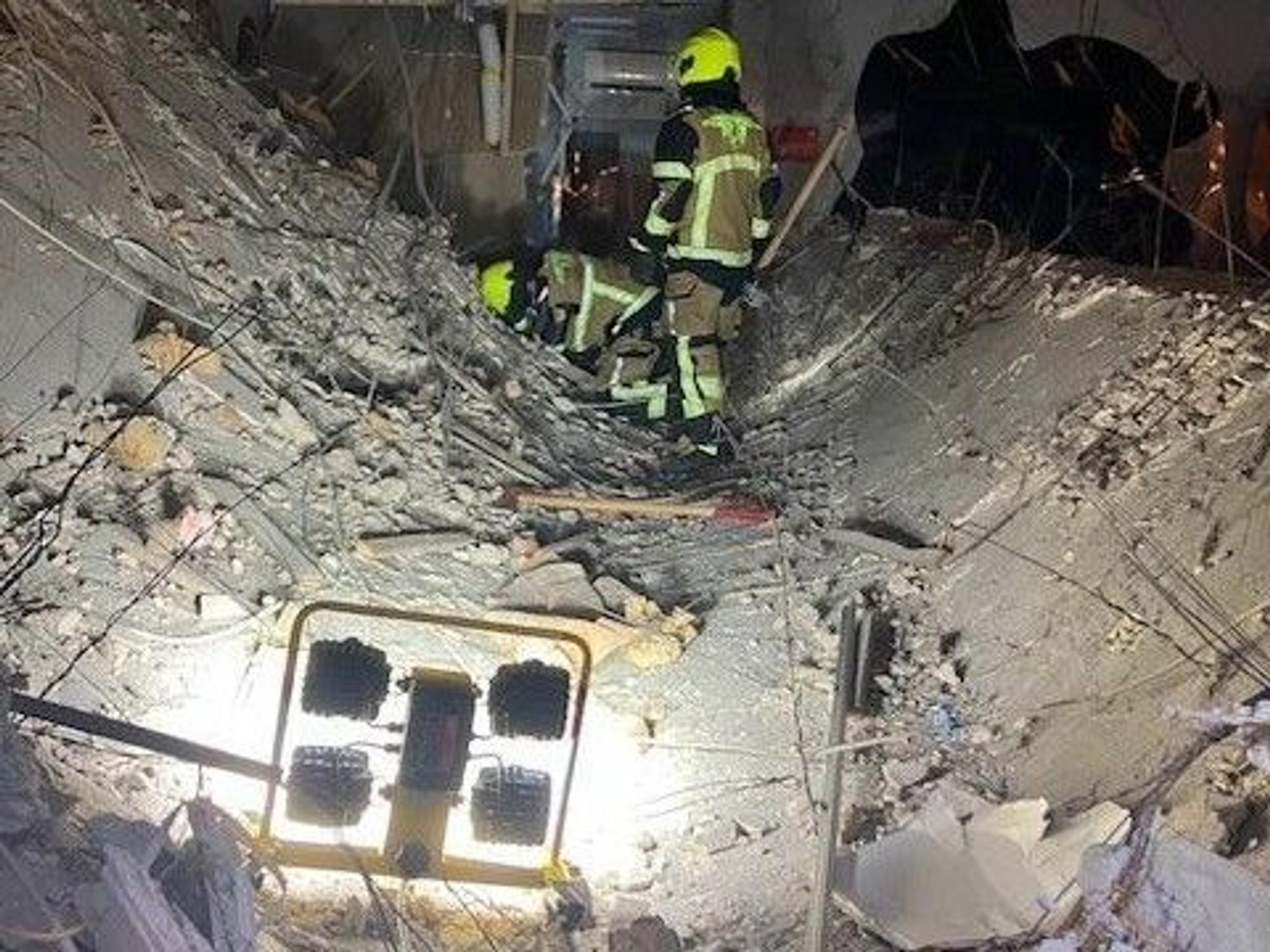 Ein Feuerwehrmann der Feuerwehr Oberhausen steht auf einer eingestürzten Decke eines Ladenlokals.
