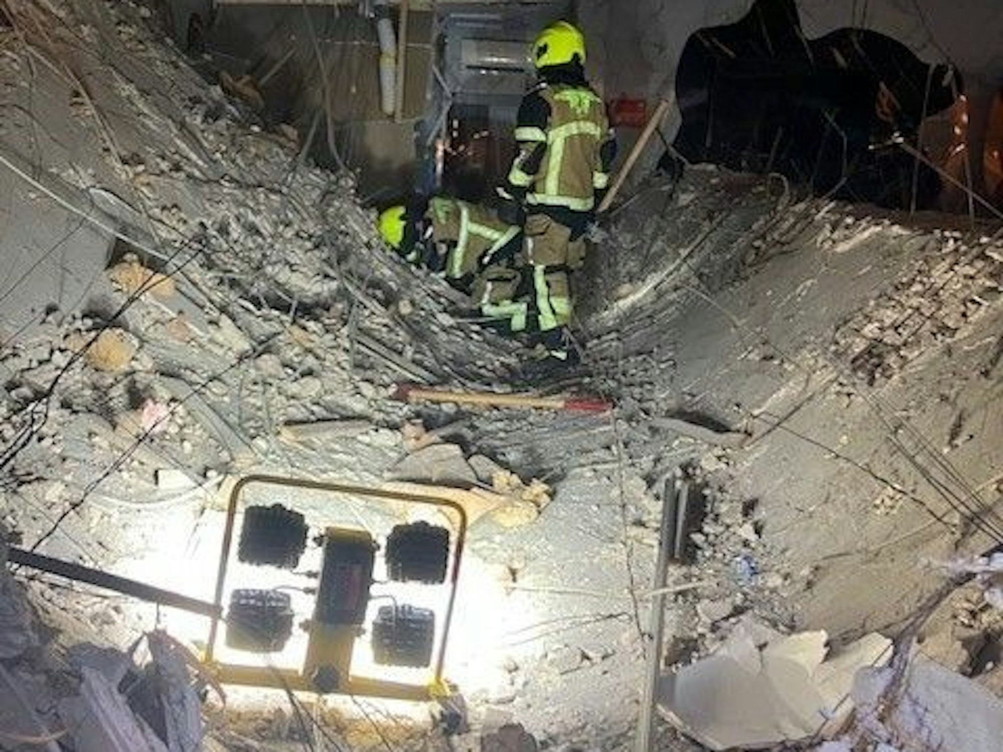 Ein Feuerwehrmann der Feuerwehr Oberhausen steht auf einer eingestürzten Decke eines Ladenlokals.