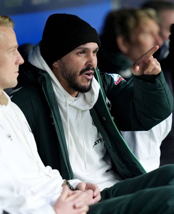 Leonardo Bittencourt sitzt auf der Auswechselbank und zeigt etwas.
