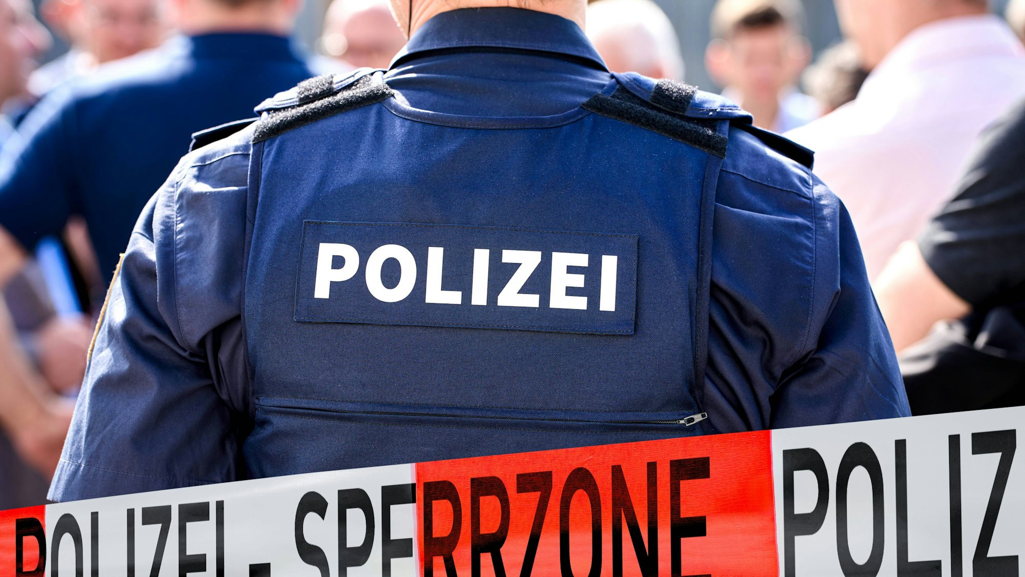 Polizist in Uniform, Absperrung mit SPERRZONE, Menschenmenge