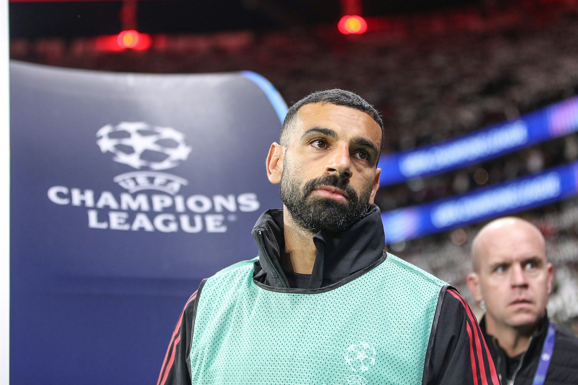 Mohamed Salah steht in einem Leibchen für Auswechselspieler vor einem Tor, auf dem das Champions-League-Logo aufgedruckt ist.