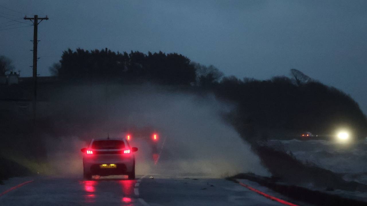 Zwei Fahrzeuge sind im Dunkeln auf einer überfluteten Straße unterwegs.