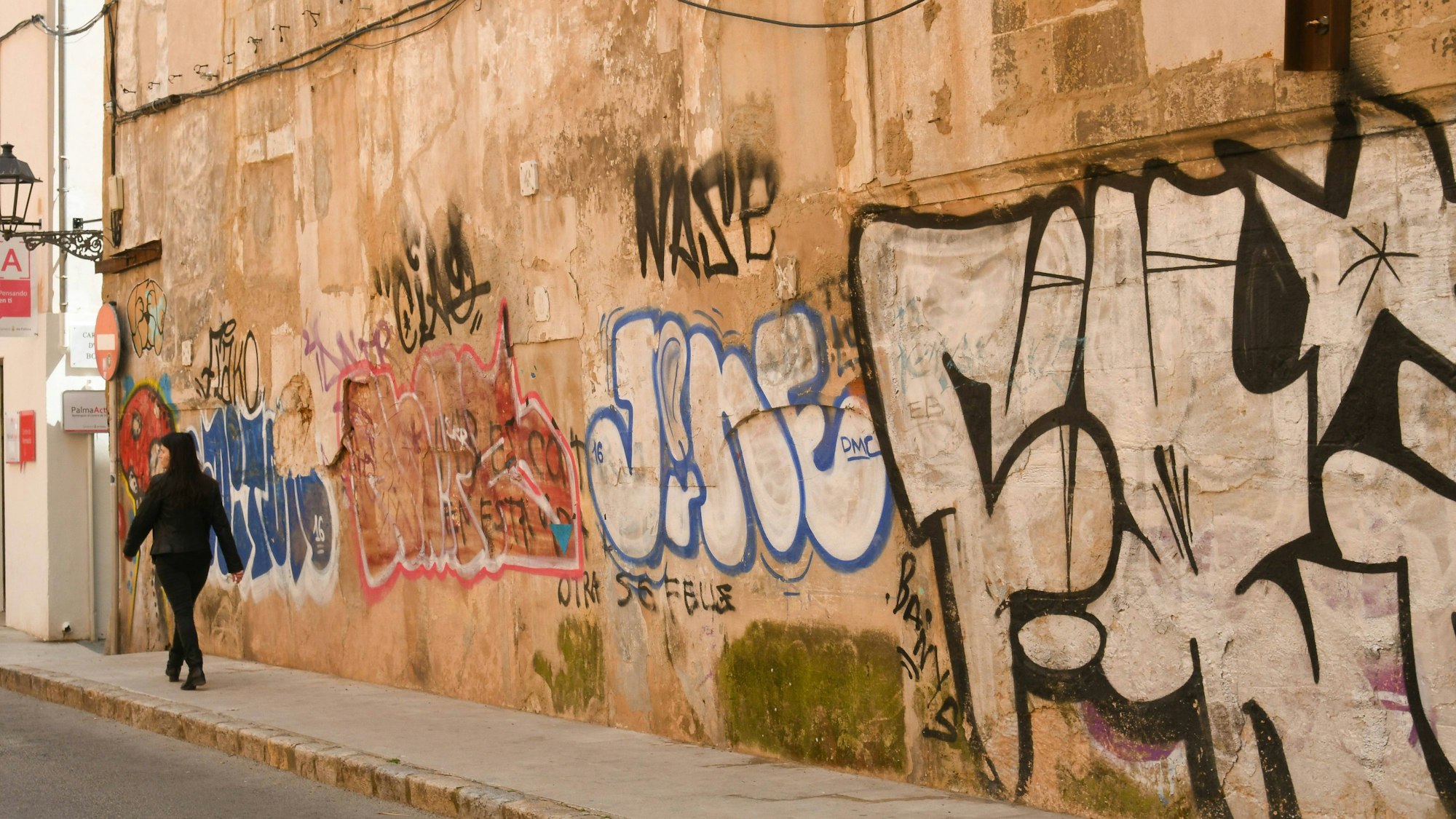 Graffiti an einer Hauswand und gehende Person (Symbolbild)
