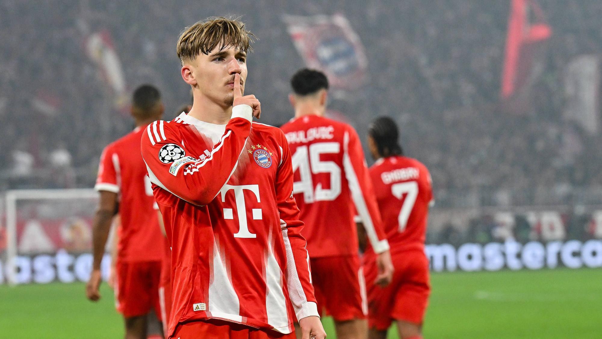 Lennart Karl hält sich bei einem Spiel des FC Bayern den Zeigefinger vor den Mund.