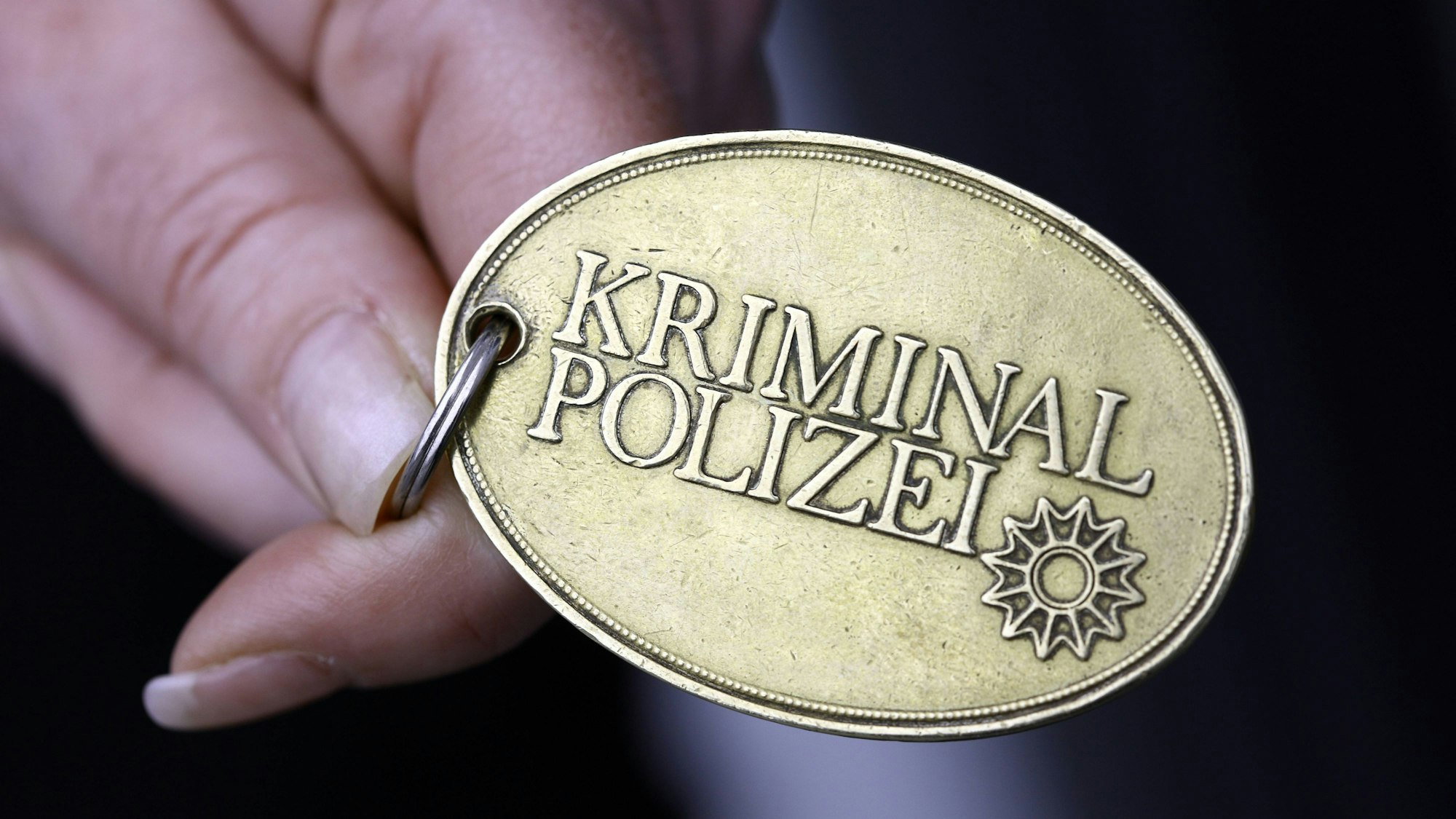 Hand hält goldene ovale Dienstmarke der Kriminalpolizei