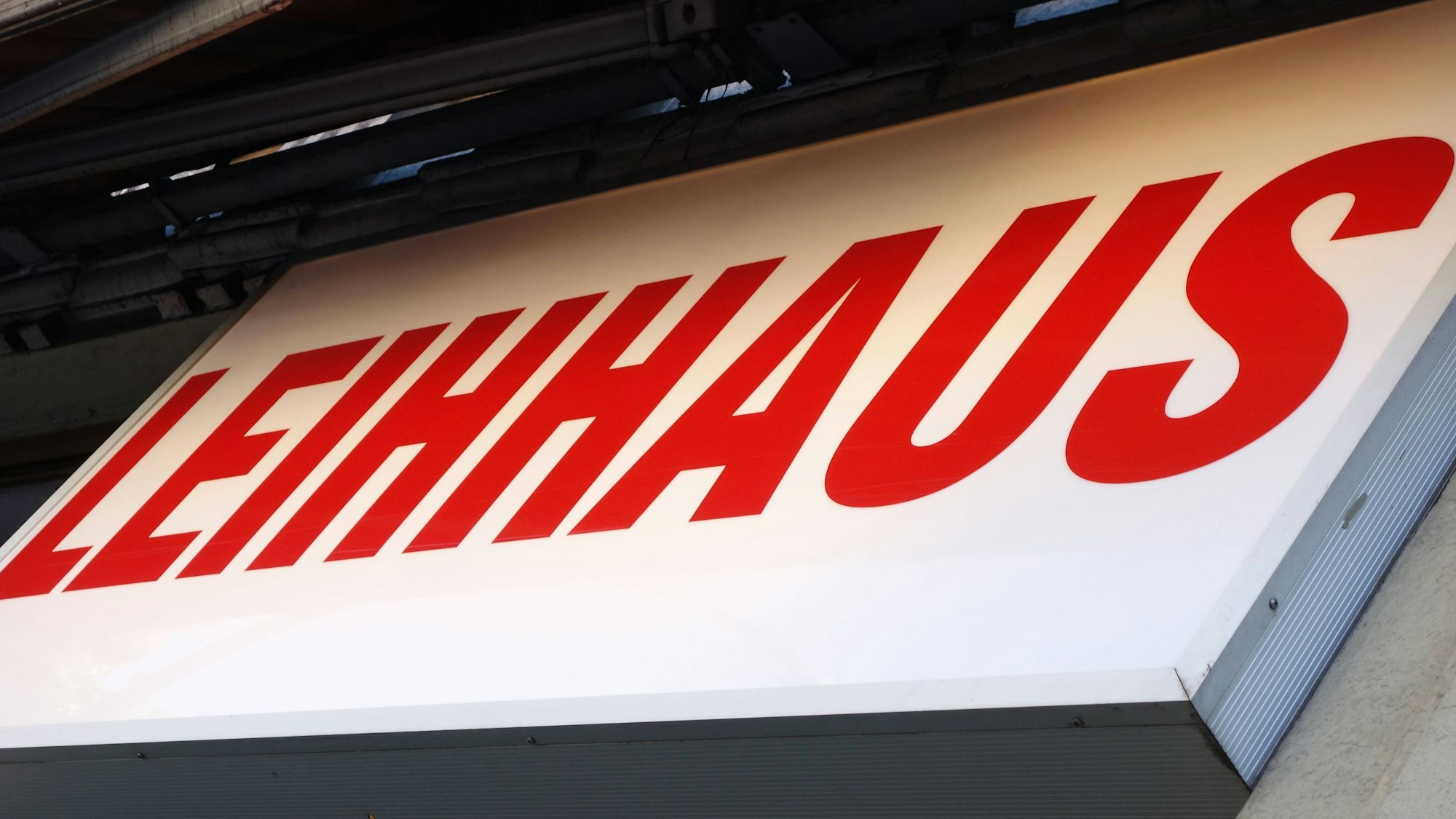 Beleuchtetes Werbeschild mit roter Schrift an einem Gebäude