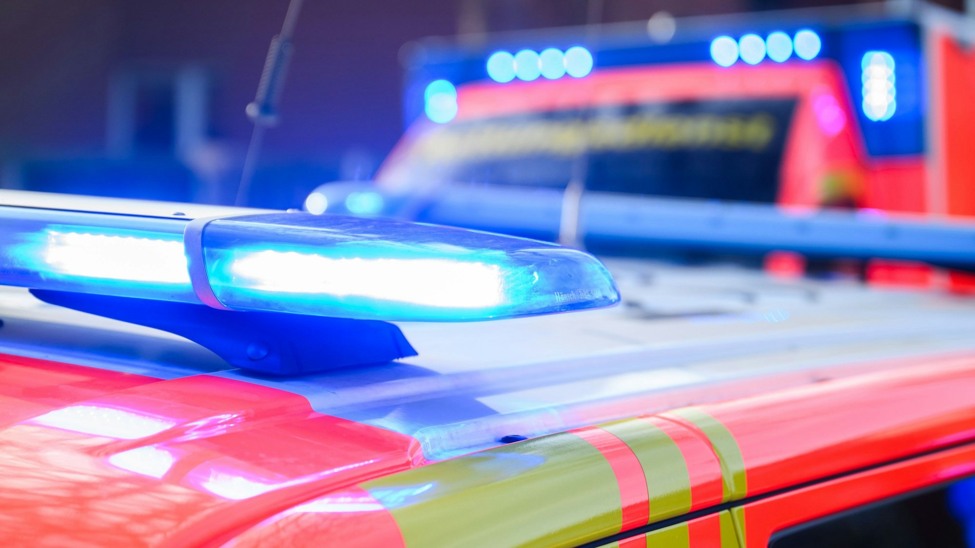Blaulichter leuchten an einer Einsatzstelle auf einem Notarzt-Fahrzeug und einem Rettungswagen.