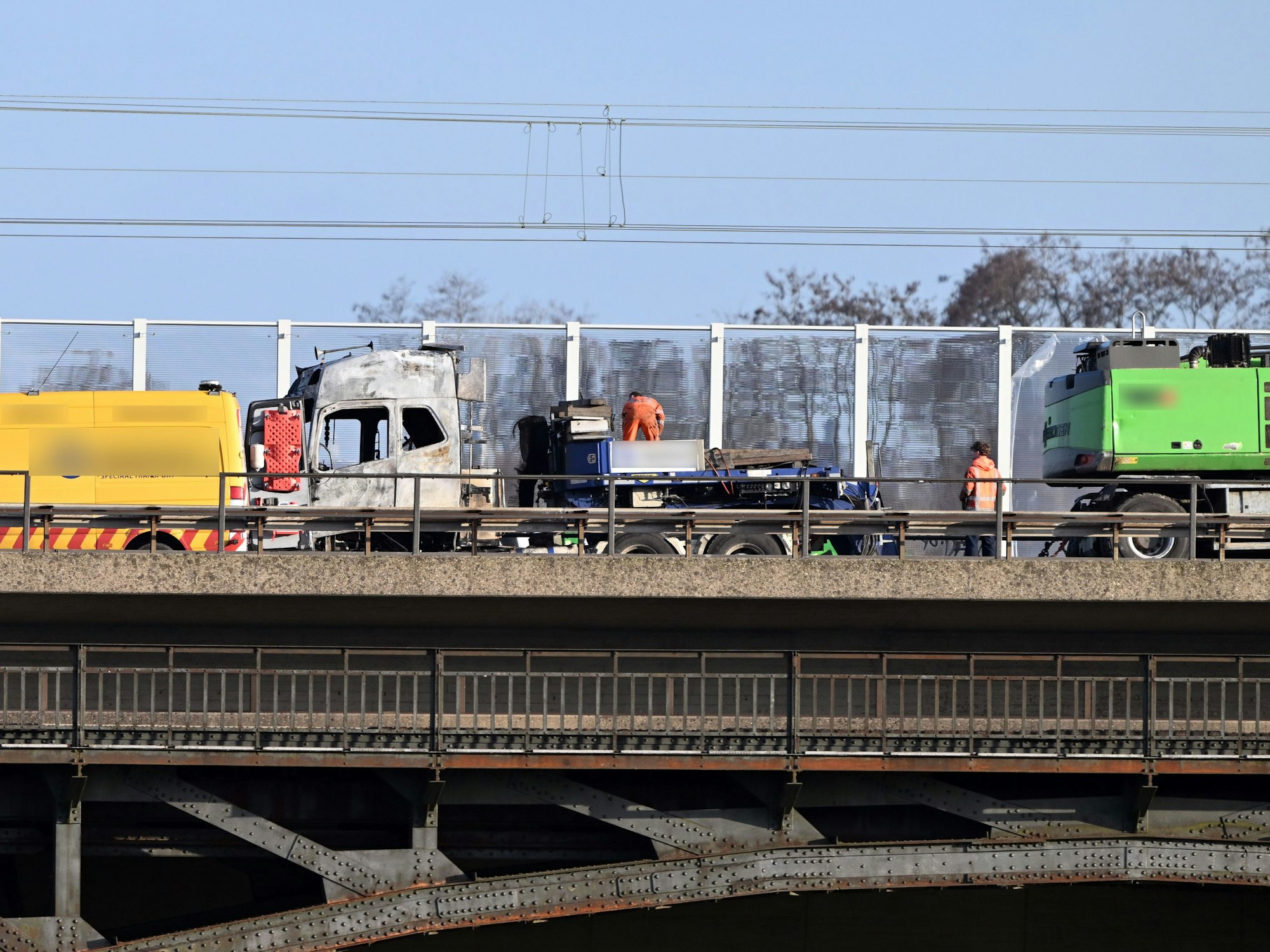 Auf einer Brücke steht ein ausgebrannter Lkw.