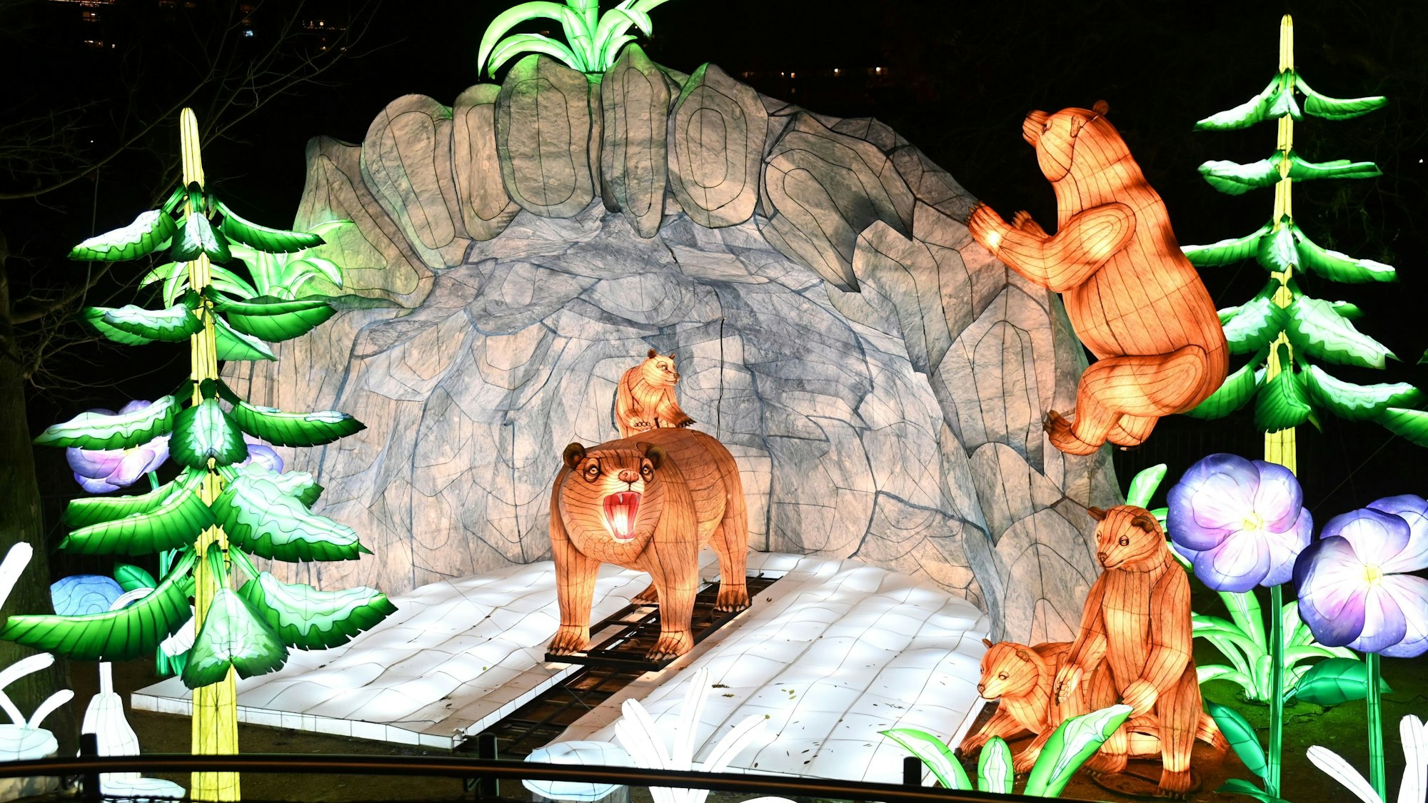 Fünf leuchtende Bären vor einer Höhle.