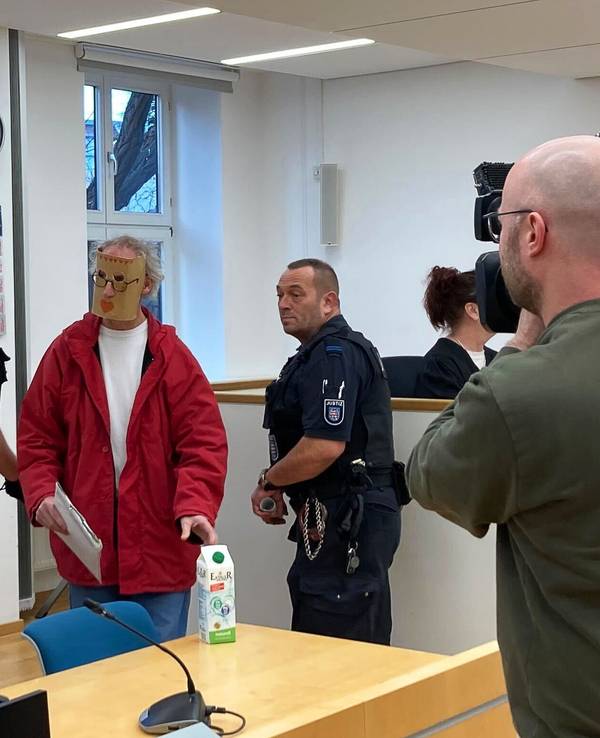 Eine der beiden Angeklagten (2.v.l) kommt zum Prozessauftakt mit einer Maske vor ihrem Gesicht in den Verhandlungssaal des Landgerichts Erfurt. Weil sie eine junge Frau nackt in einer Holzkiste gesperrt haben sollen, sind ein Mann und eine Frau aus Thüringen am Landgericht Erfurt angeklagt.