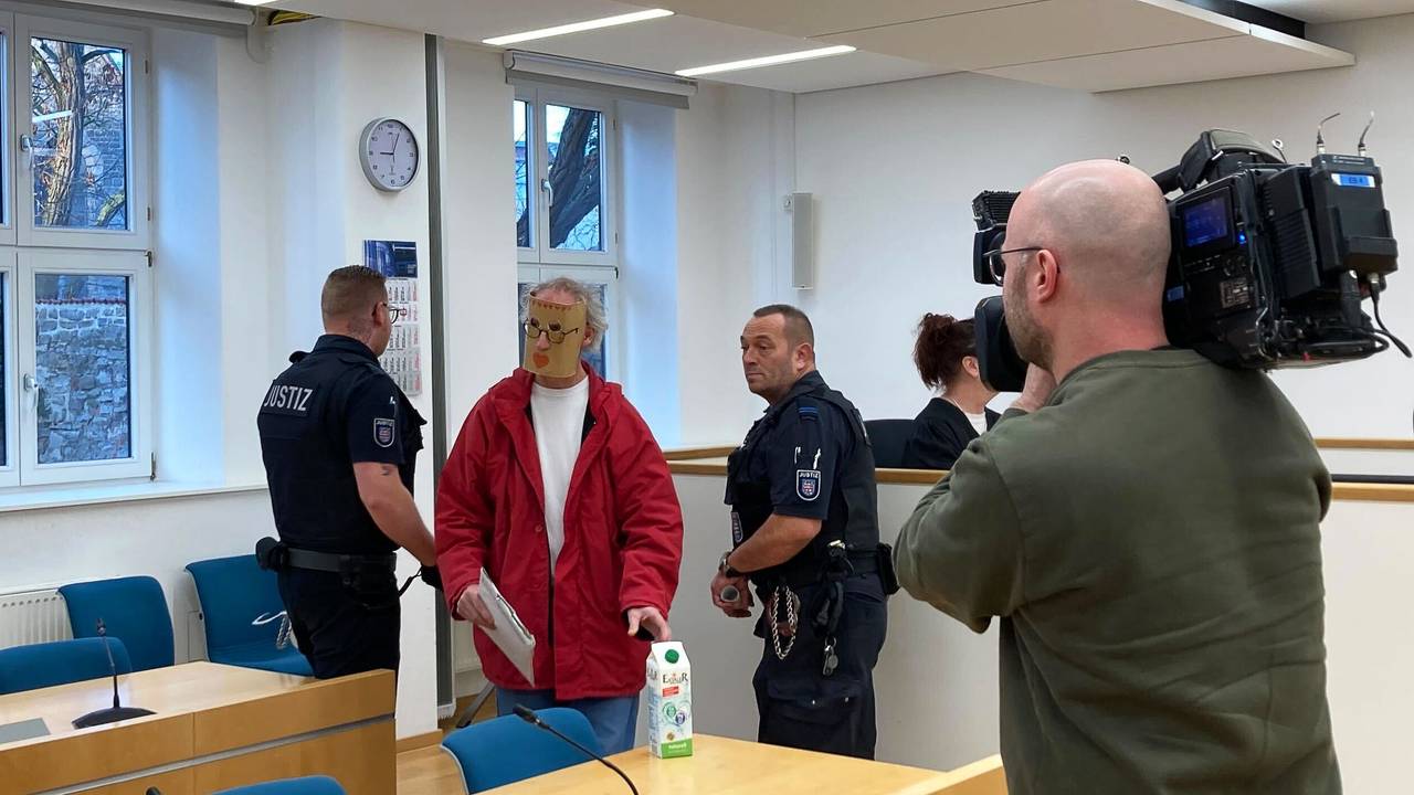 Eine der beiden Angeklagten (2.v.l) kommt zum Prozessauftakt mit einer Maske vor ihrem Gesicht in den Verhandlungssaal des Landgerichts Erfurt. Weil sie eine junge Frau nackt in einer Holzkiste gesperrt haben sollen, sind ein Mann und eine Frau aus Thüringen am Landgericht Erfurt angeklagt.