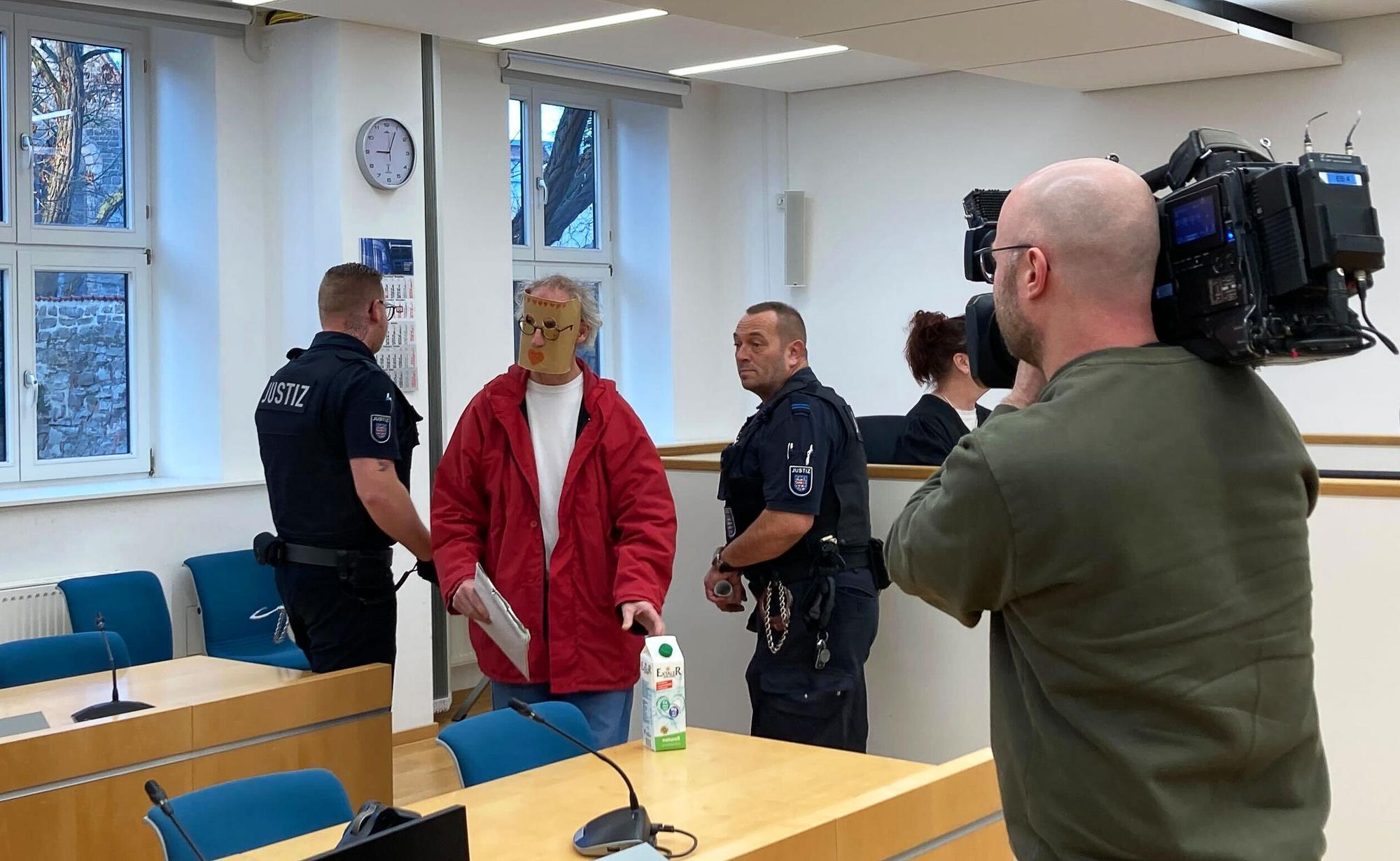 Eine der beiden Angeklagten (2.v.l) kommt zum Prozessauftakt mit einer Maske vor ihrem Gesicht in den Verhandlungssaal des Landgerichts Erfurt. Weil sie eine junge Frau nackt in einer Holzkiste gesperrt haben sollen, sind ein Mann und eine Frau aus Thüringen am Landgericht Erfurt angeklagt.