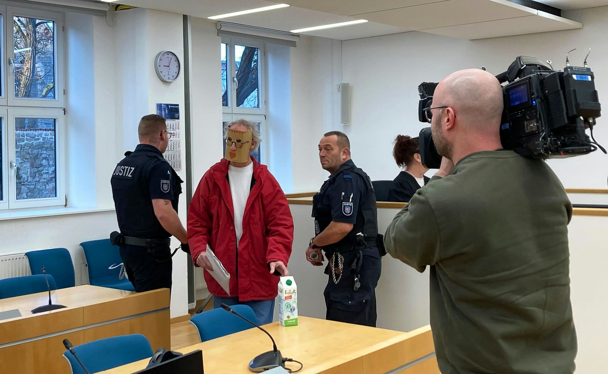 Eine der beiden Angeklagten (2.v.l) kommt zum Prozessauftakt mit einer Maske vor ihrem Gesicht in den Verhandlungssaal des Landgerichts Erfurt. Weil sie eine junge Frau nackt in einer Holzkiste gesperrt haben sollen, sind ein Mann und eine Frau aus Thüringen am Landgericht Erfurt angeklagt.