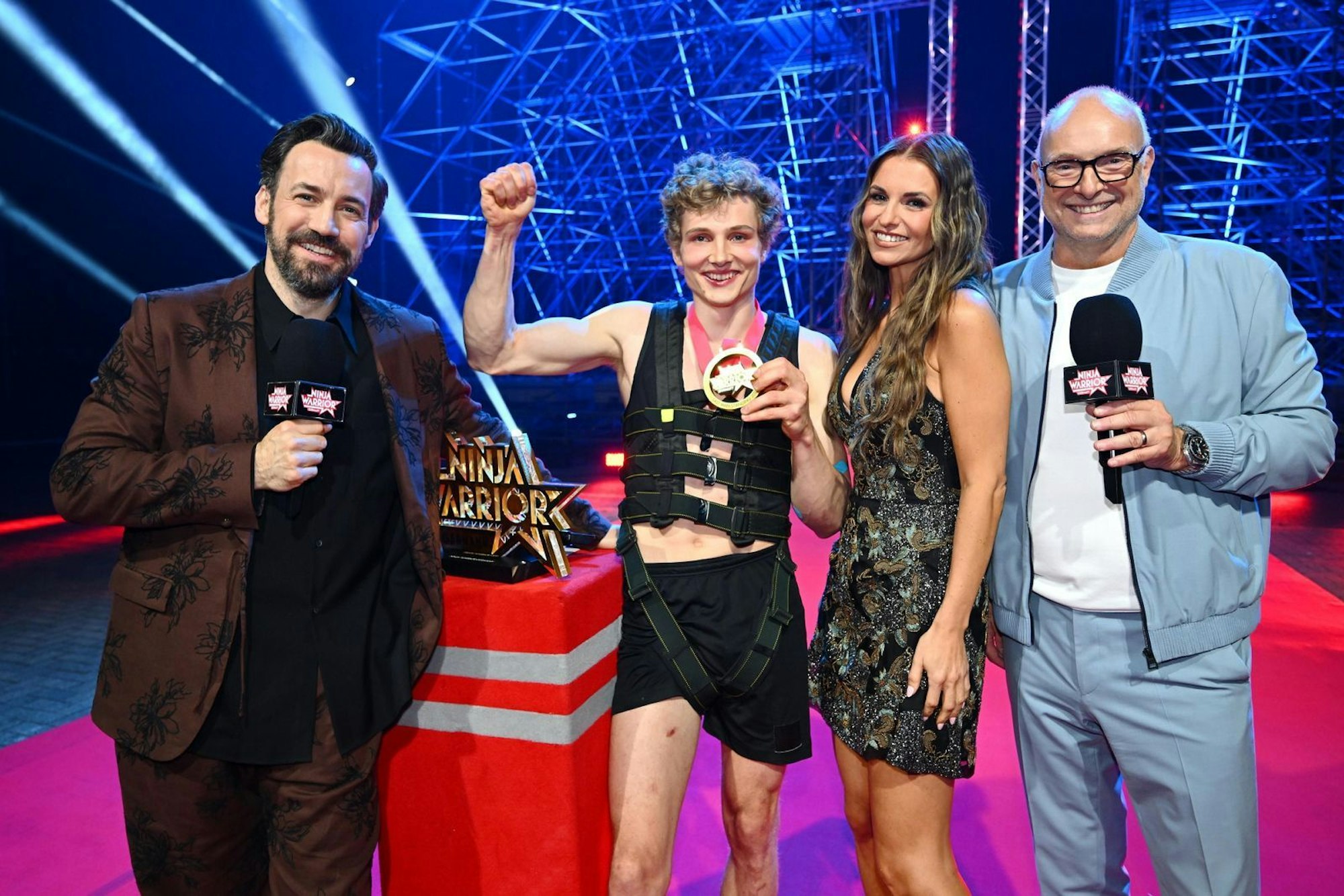 Der Sieger der Jubiläumsstaffel freut sich mit den Moderatoren Frank Buschmann und Jan Köppen sowie Field Reporterin Laura Wontorra über den Titel als Last Man Standing und die Siegprämie von 25.000 Euro. (Bild: RTL)