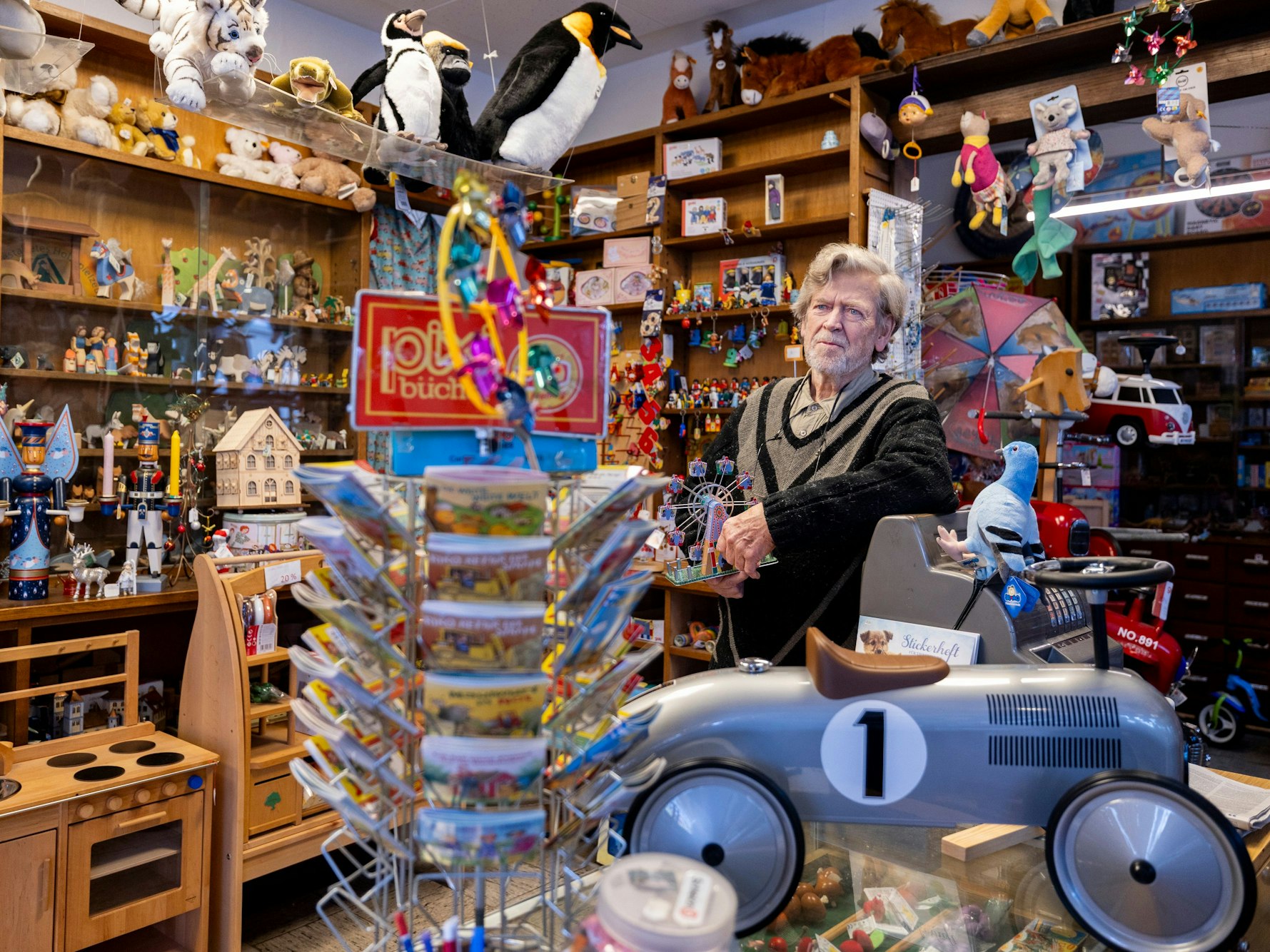 Ein Mann steht in einem Spielzeugladen, vor sich eine Miniausgabe eines BMW-Rennwagens.