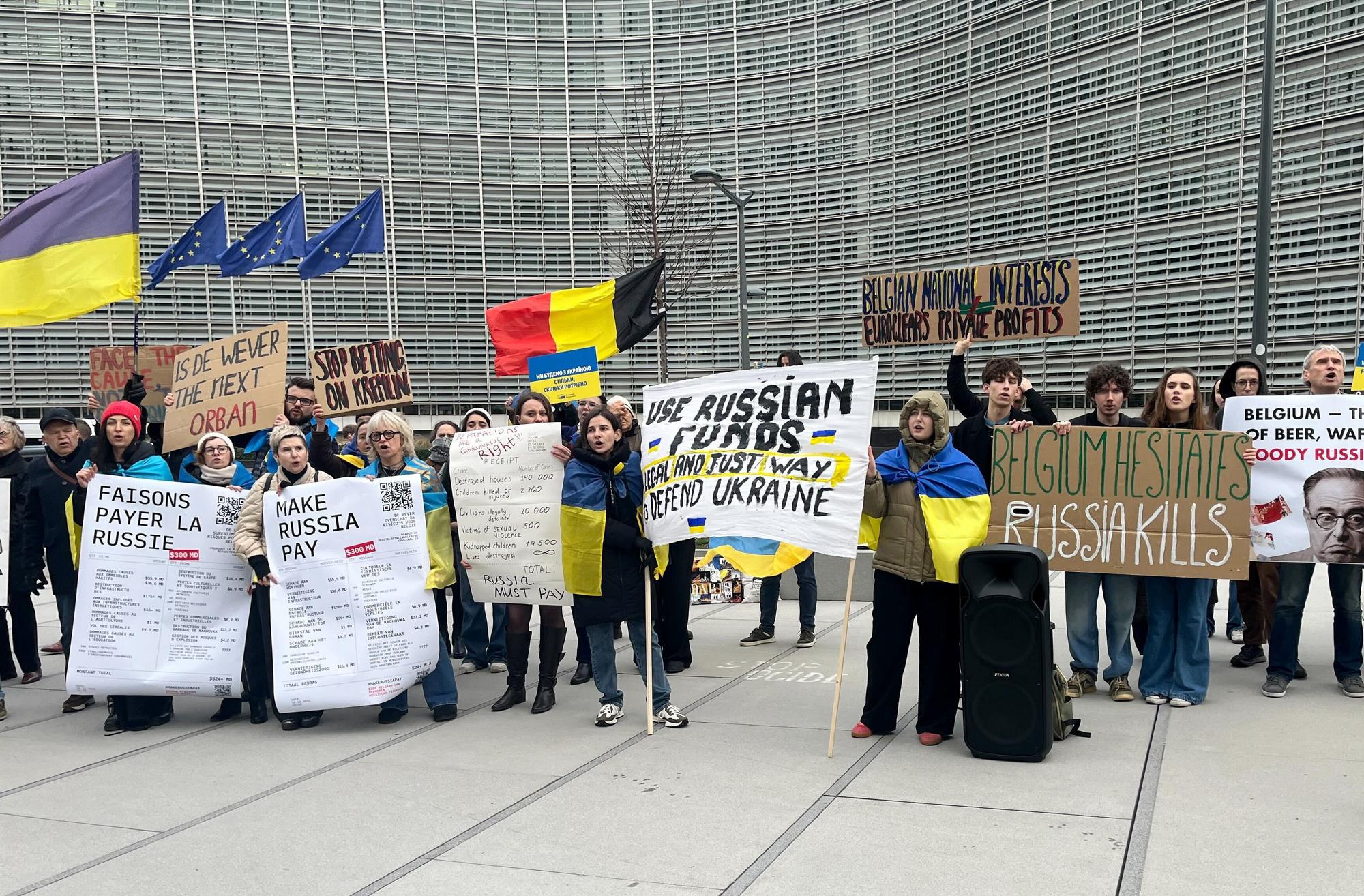 Menschen demonstrieren vor dem EU-Ratsgebäude für die Verwendung von in der EU festgesetztem russischen Geld für die Ukraine.