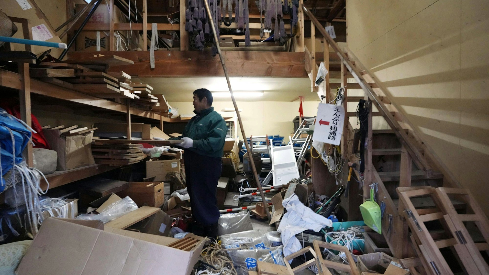 Mann räumt Raum eines Schreins nach Erdbeben auf