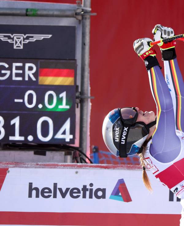 Emma Aicher jubelt im Zieleinlauf und reckt die Skistöcke in die Luft.