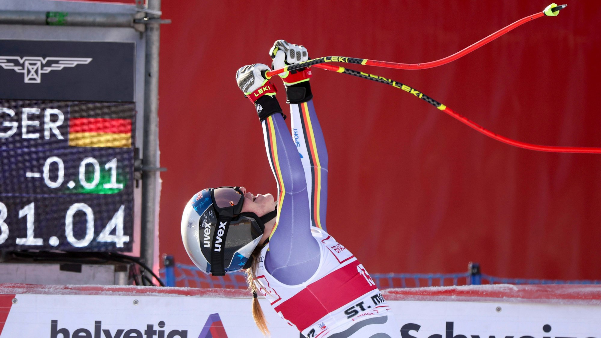 Emma Aicher jubelt im Zieleinlauf und reckt die Skistöcke in die Luft.