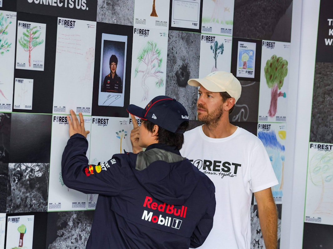 An einem Infostand spricht Sebastian Vettel mit Yuki Tsunoda.