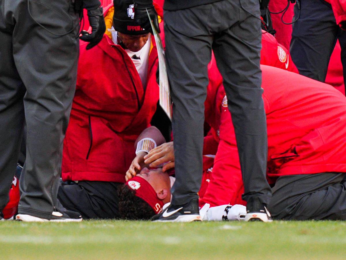 Patrick Mahomes liegt verletzt am Boden, Betreuer kümmern sich um ihn.