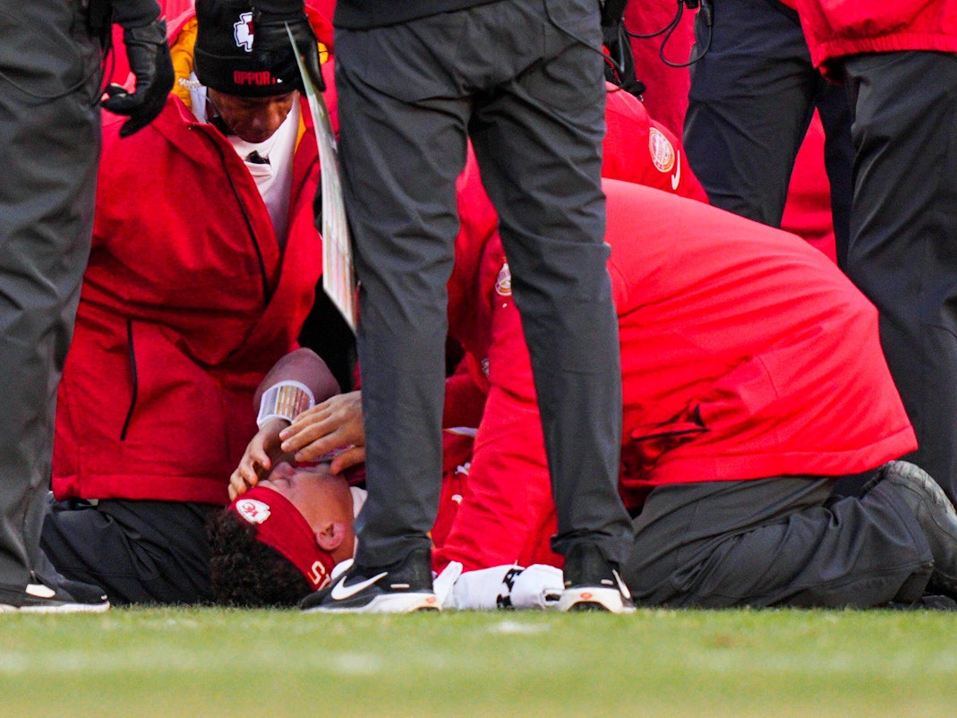 Patrick Mahomes liegt verletzt am Boden, Betreuer kümmern sich um ihn.
