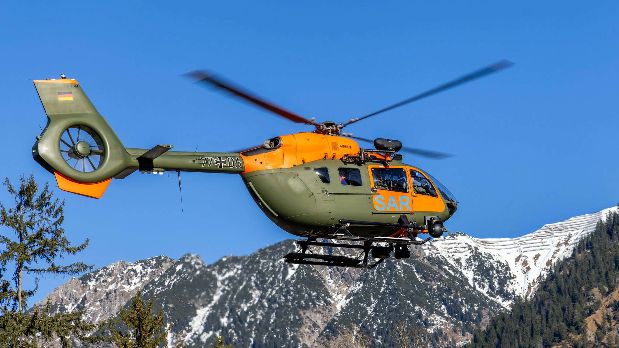 SAR Hubschrauber im Flug über die verschneiten Alpen