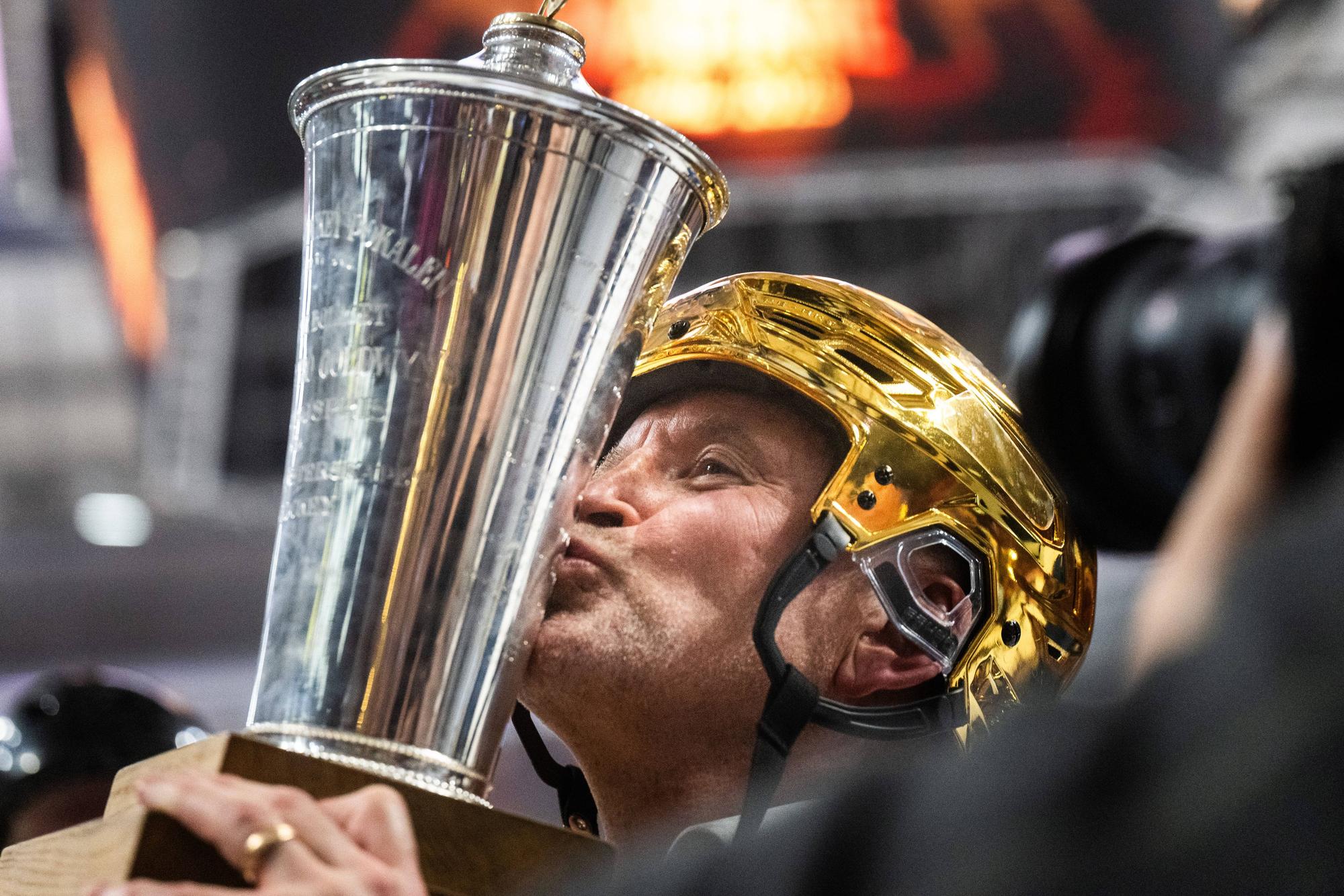 Thomas Berglund küsst mit goldenem Helm den Meisterpokal.