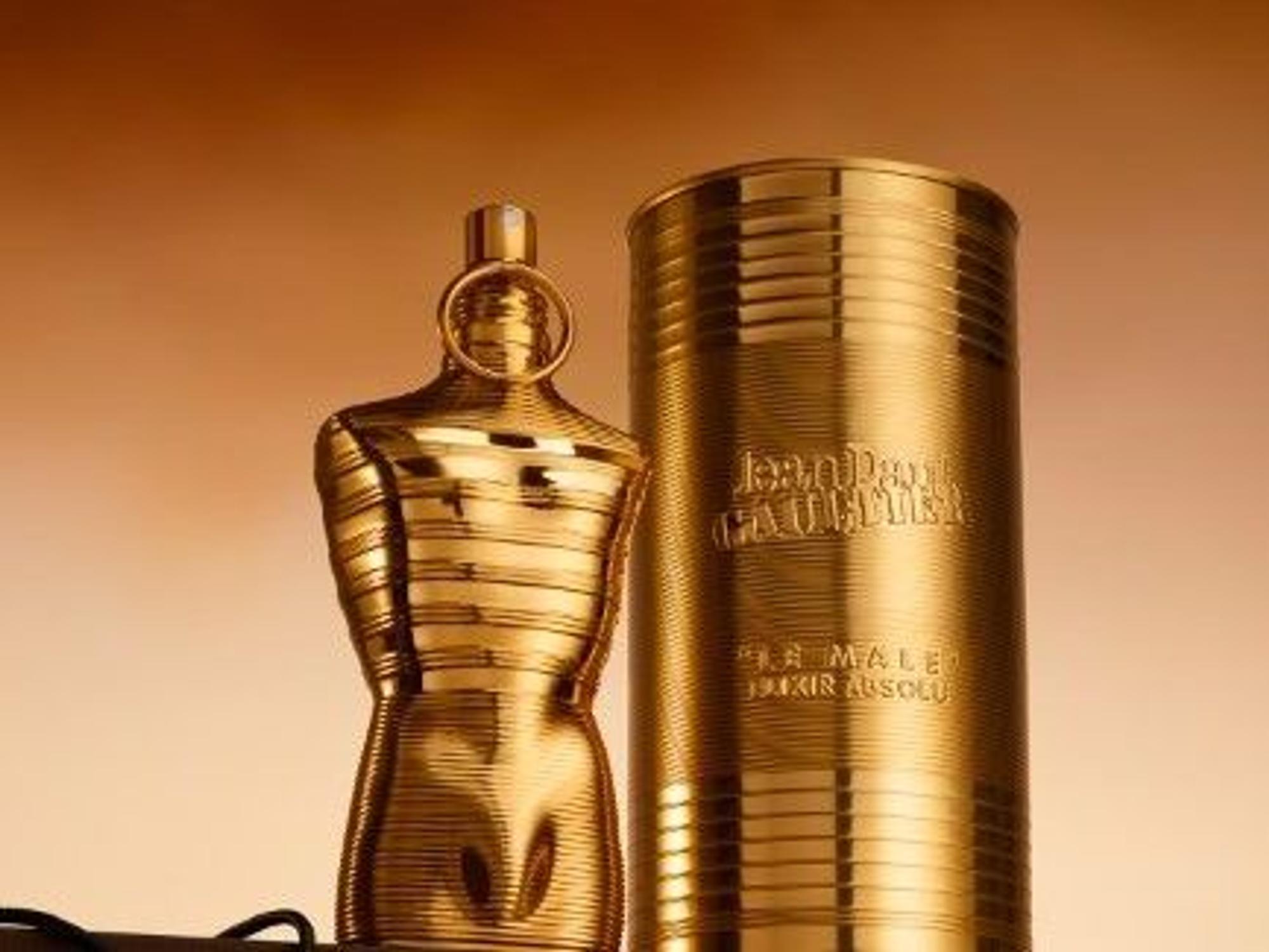 Ein goldener Flakon in Form eines Männertorsos steht neben einer goldenen Dose