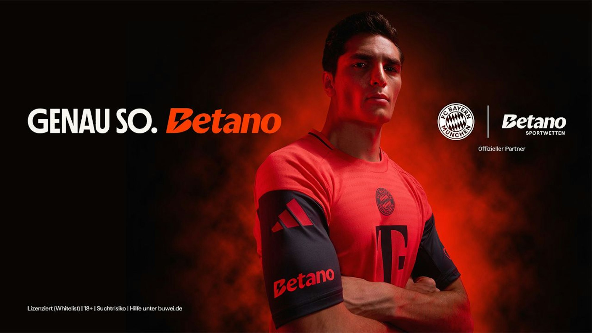 Ein Fußballspieler in einem roten Trikot, der die Arme verschränkt.