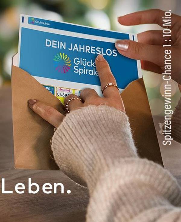 Eine Frau hält ein Jahreslos der GlücksSpirale in der Hand und tut dieses in einen Umschlag.