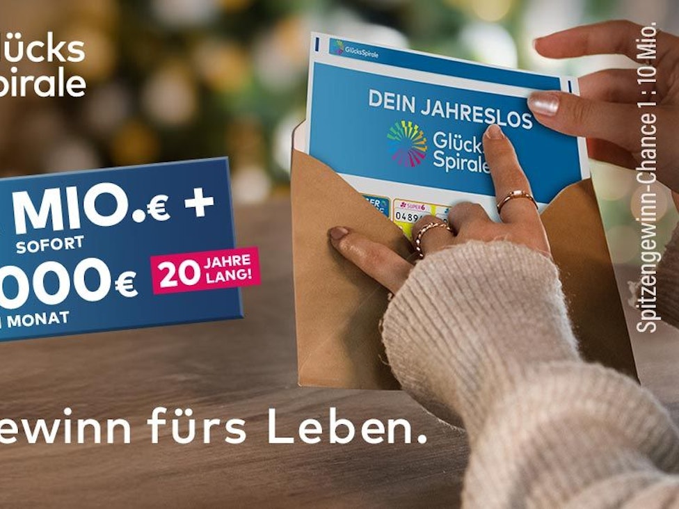 Eine Frau hält ein Jahreslos der GlücksSpirale in der Hand und tut dieses in einen Umschlag.
